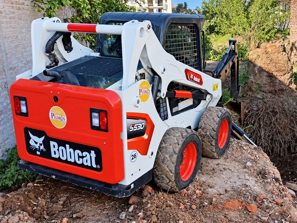 Minicargadora Bobcat volteando una pared